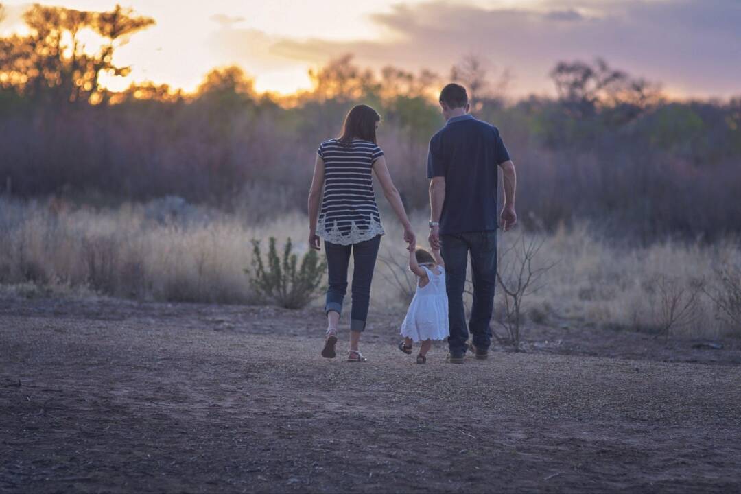 Family of three walking hand-in-hand along a path at sunset near their Chilliwack home.